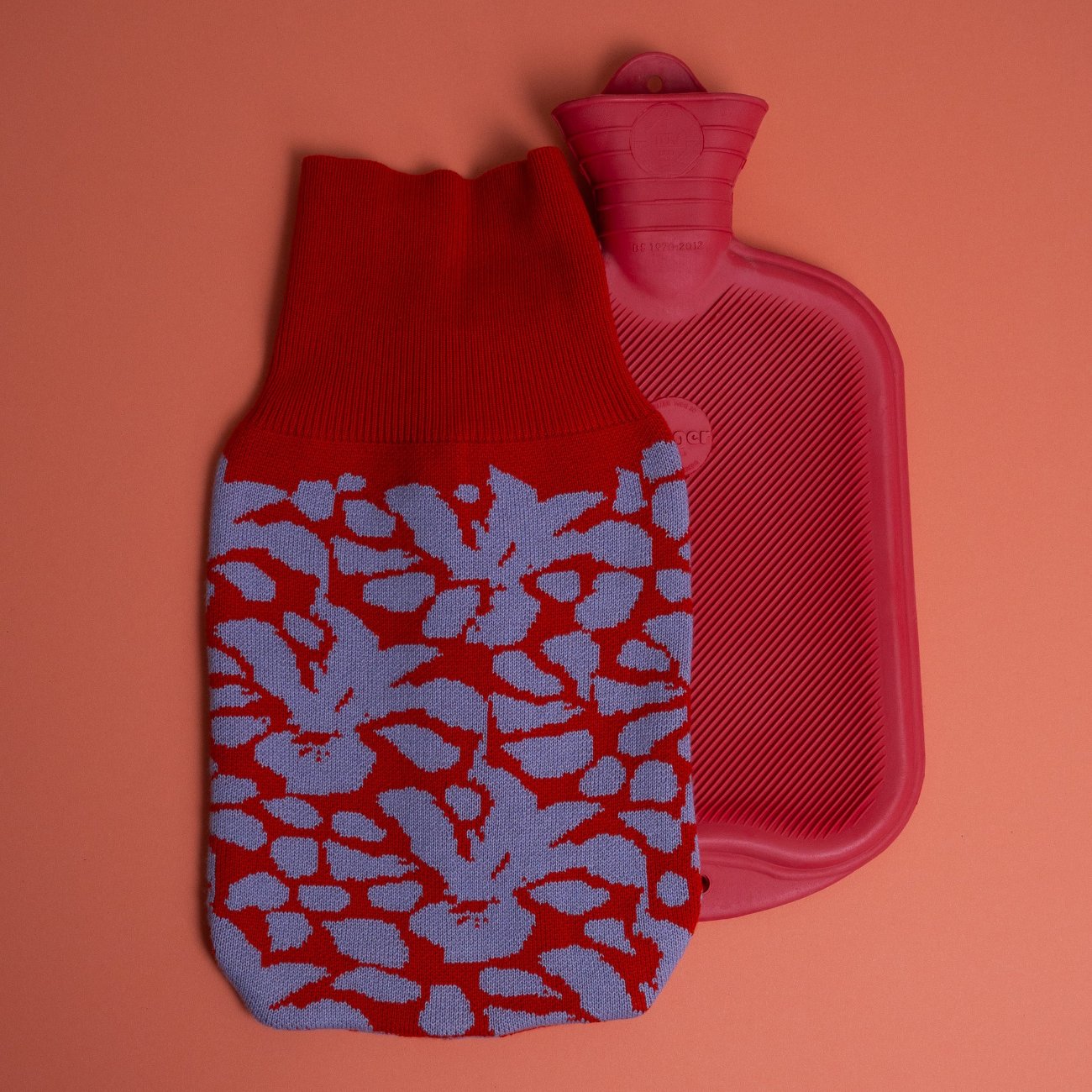 gestrickter wärmflaschenbezug mit blütenmuster in rot und flieder mit seperater roter wärmflasche